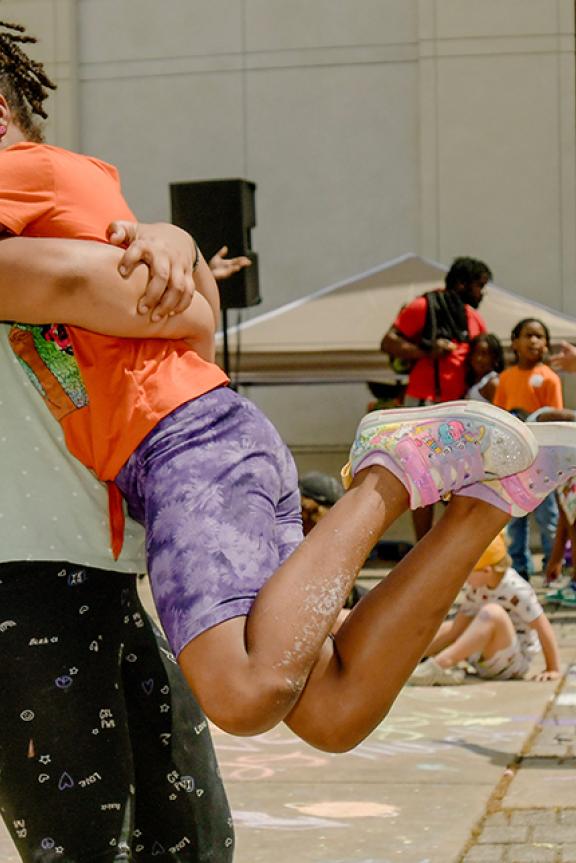 A parent and child hugging at a chalk art event outside the Memphis Brooks Museum of Art.