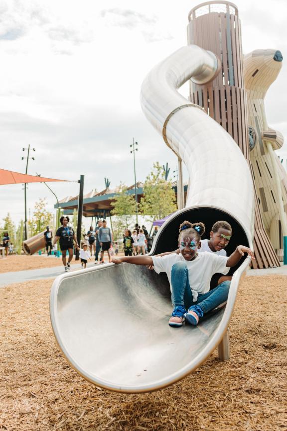 Children sliding down the tunnel slide on the playground at Tom Lee Park.