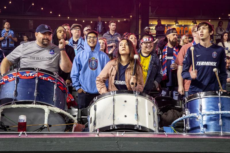 three 901 fc soccer fans beat on giant drums from fan section