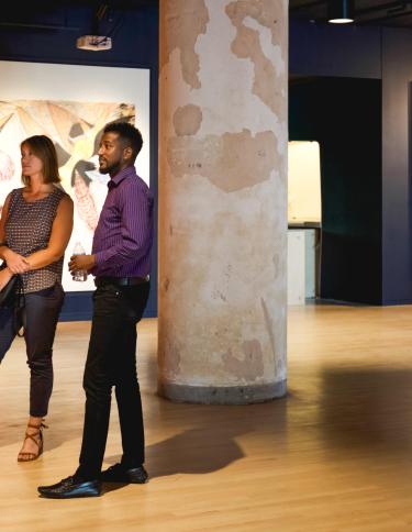 Two people stand looking at pieces in Crosstown Concourse art gallery.