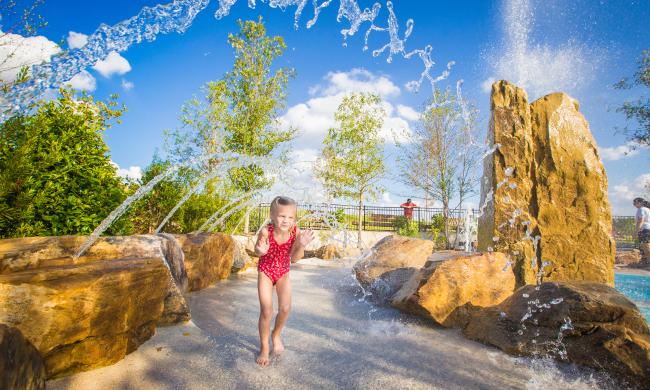 A girl running through a sprinkler at the Splash Pad at Shelby Farms Park.