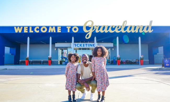 dad poses with daughter in front of welcome to Graceland sign