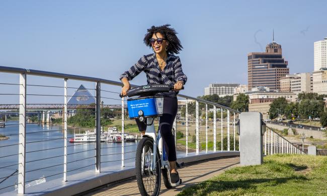 woman rides along riverfront on bike