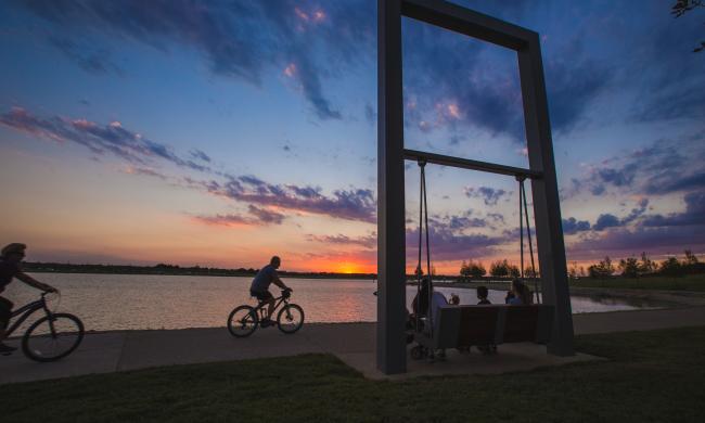 Cyclist riding next to the lake at Shelby Farms during sunset.