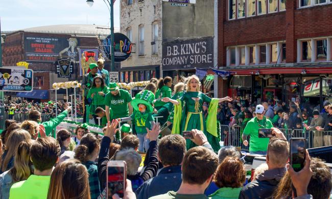 People dressed in green on a parade float passing crowds on Beale Street for the Silky Sullivan St. Paddy's Day Parade.