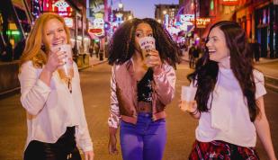 three girls drinking while walking down Beale street