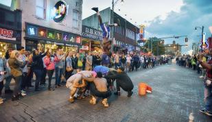 Beale Street Flippers flip over crouched group on Beale Street with a crowd watching.